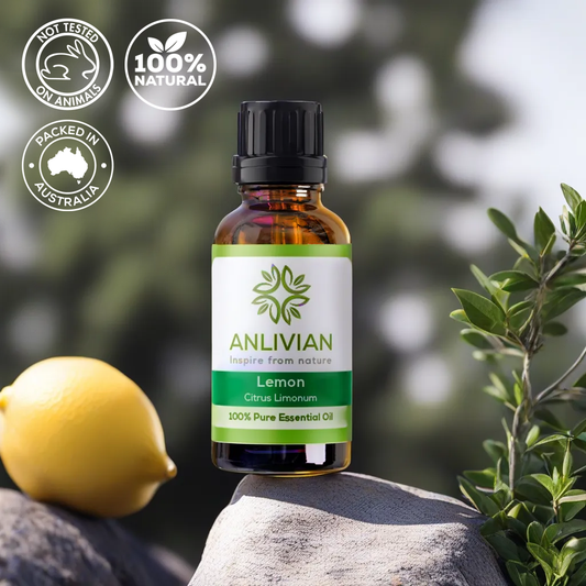 A bottle of Anlivian brand Lemon Essential Oil placed on a rock with lemon fruit and green leaves in the background.