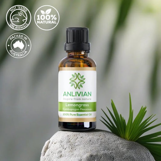 Lemongrass essential oil bottle on a rock with green leaves in the background
