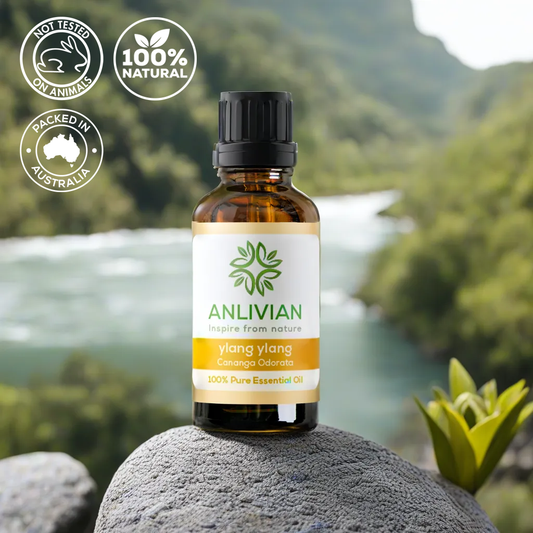 A bottle of Anlivian Ylang Ylang Essential Oil placed on a rock with a scenic background.