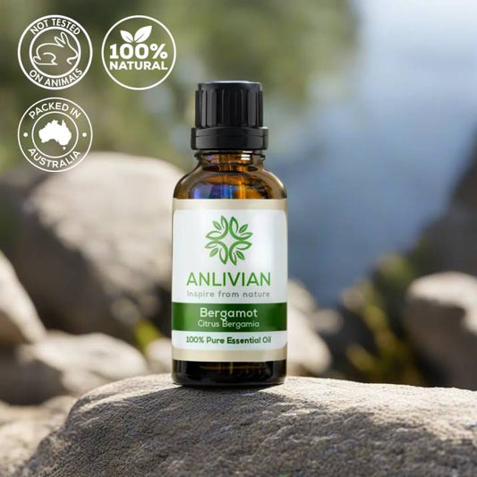 Anlivian Bergamot Pure Essential Oil bottle resting on a grey rock with icons indicating Not Tested on Animals, 100% Natural, and Packed in Australia.